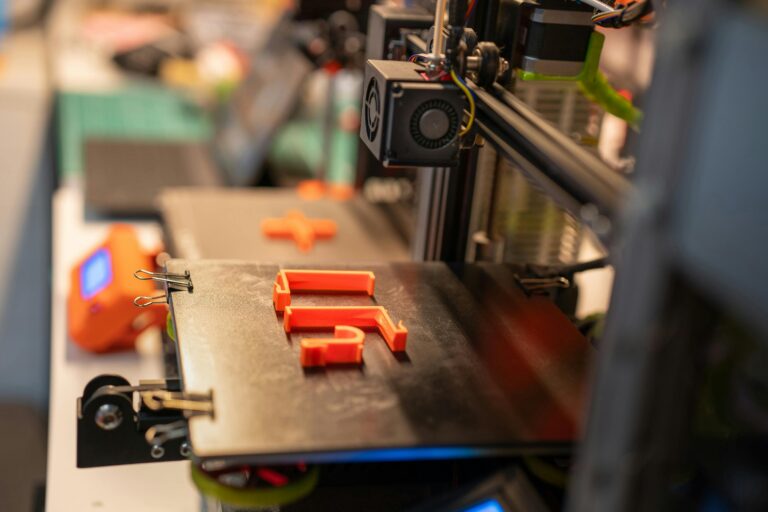 Detailed view of a 3D printer creating an orange plastic part showcasing advanced technology.